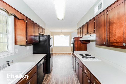 a kitchen with wooden cabinets and white counters and a black refrigerator