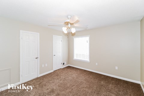 a bedroom with carpet and a ceiling fan and two doors