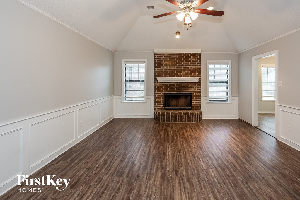 A room with a brick fireplace and wooden floors.