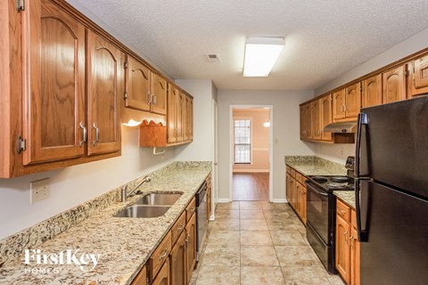 A kitchen with wooden cabinets and a black refrigerator.