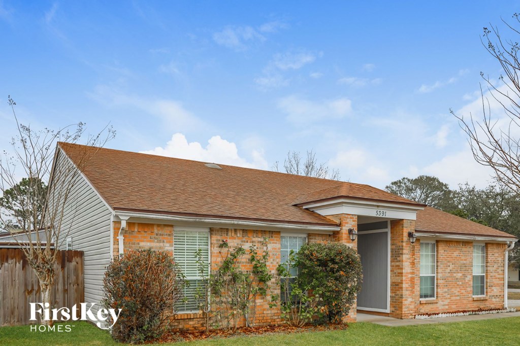 a small brick house with a yard and a fence