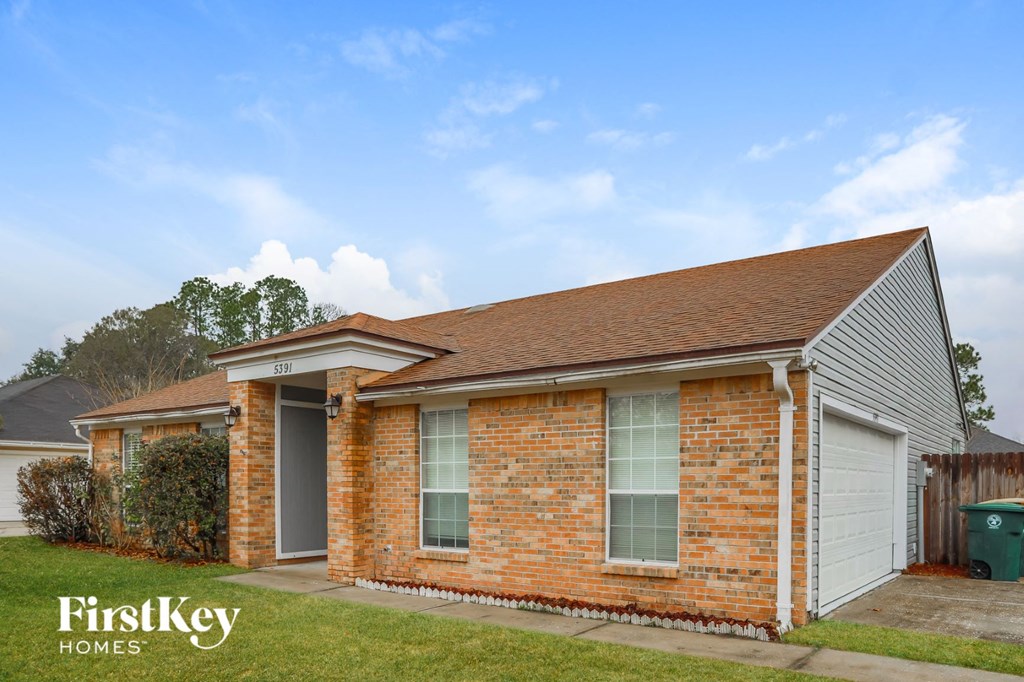 a small brick house with a garage and a lawn