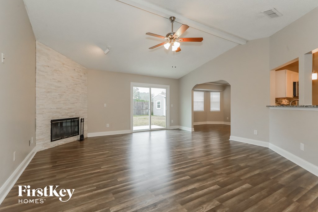 an empty living room with a fireplace and a ceiling fan
