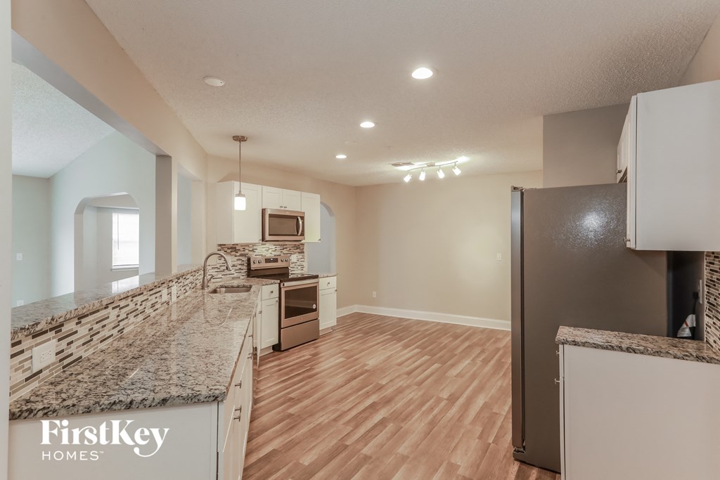 a kitchen with granite counter tops and a stainless steel refrigerator