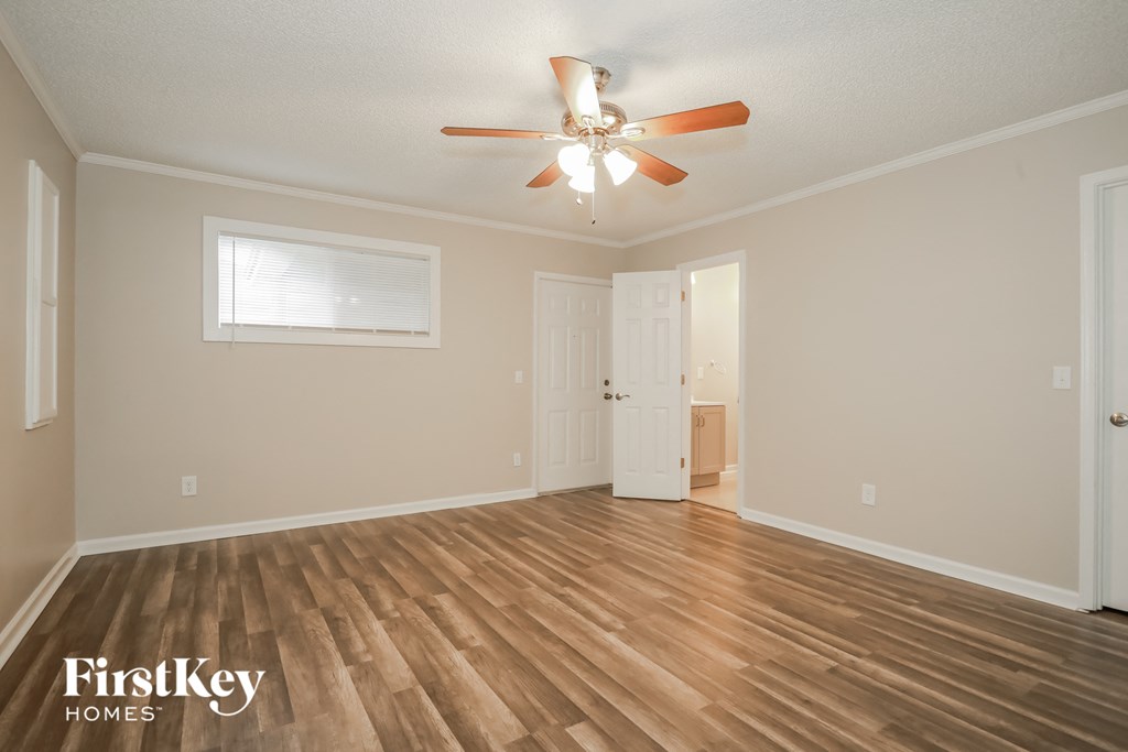 the spacious living room with hardwood flooring and a ceiling fan