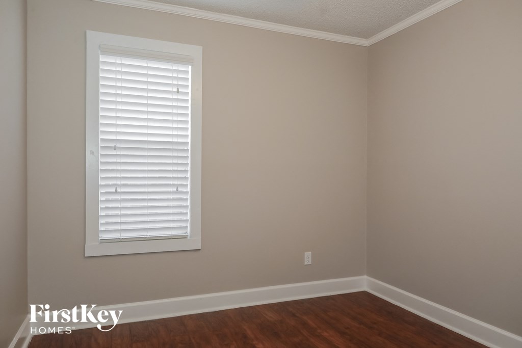 the corner of a room with a window and wooden floors