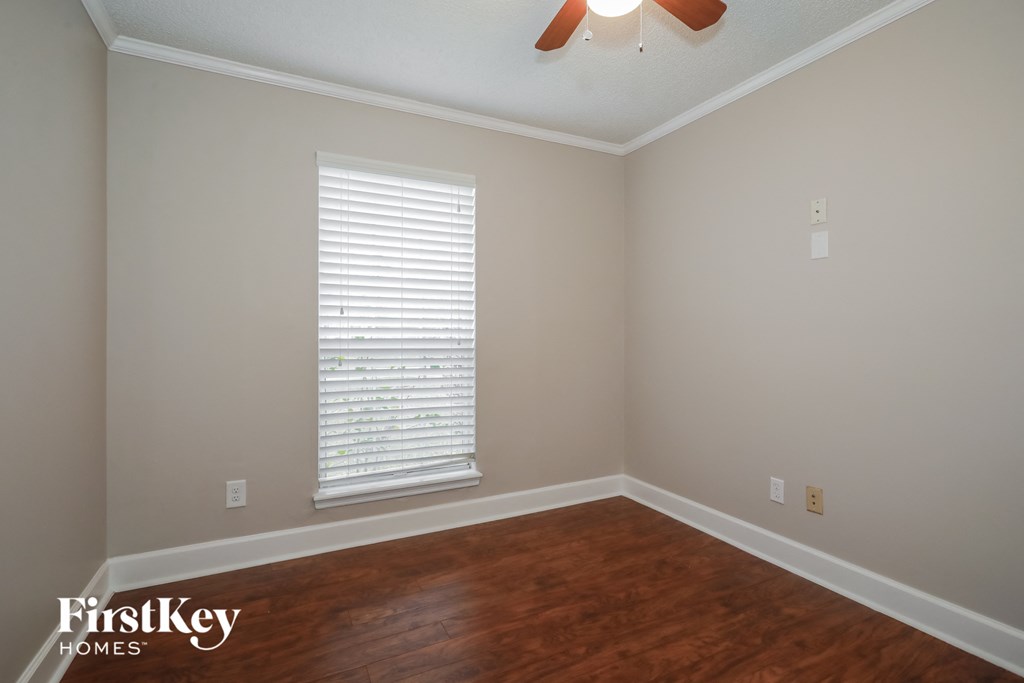 a bedroom with wood floors and a window and a ceiling fan