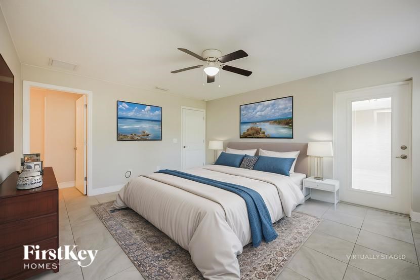A bedroom with a large bed and two pictures on the wall.
