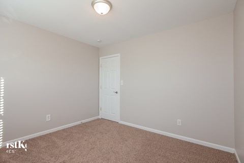 a bedroom with white walls and a white door and carpet