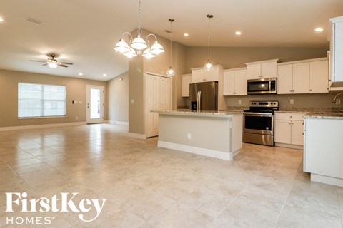 A spacious kitchen with white cabinets and appliances, and a large island in the middle.
