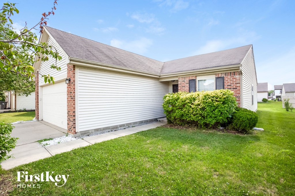 a small white and brick house with a yard and grass