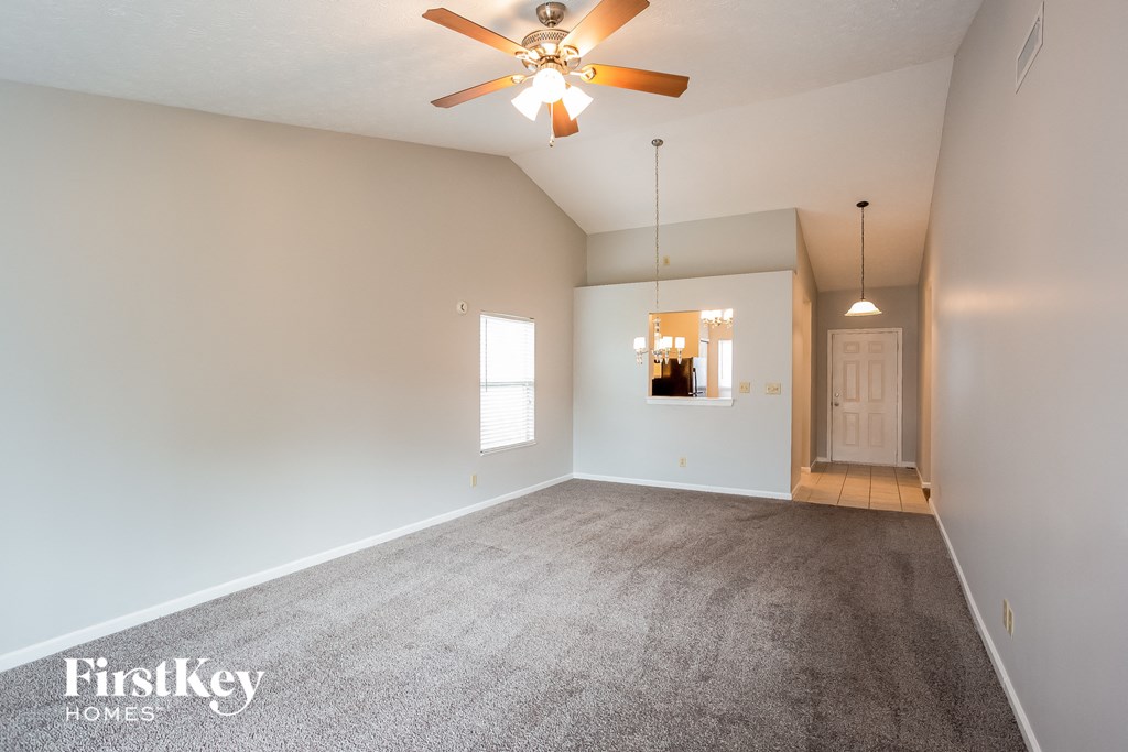 an empty living room with carpet and a ceiling fan