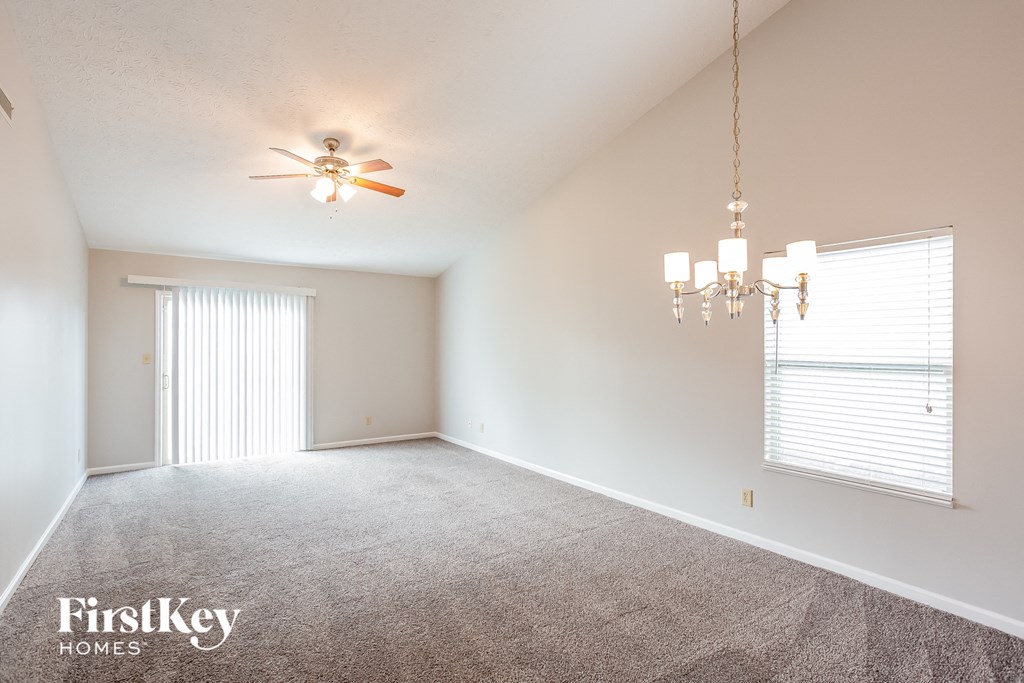 an empty living room with a ceiling fan and a window