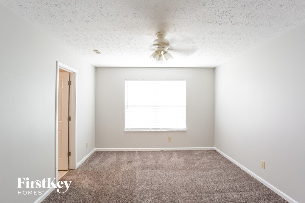 a carpeted room with a ceiling fan and a window