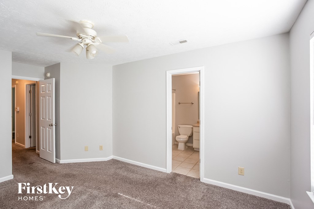 a living room with a ceiling fan and a door to a bathroom