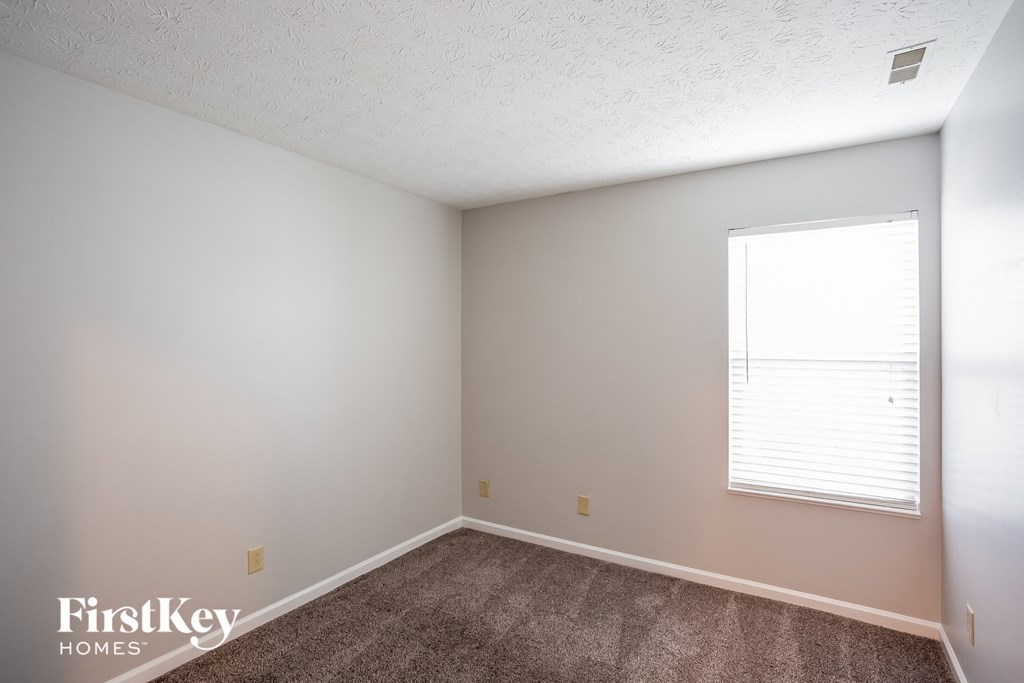 a bedroom with a carpeted floor and a window