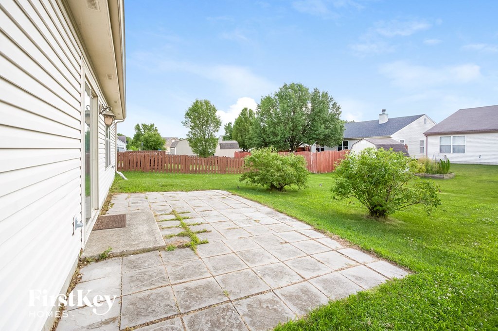 the backyard of a house with a patio and grass and a fence