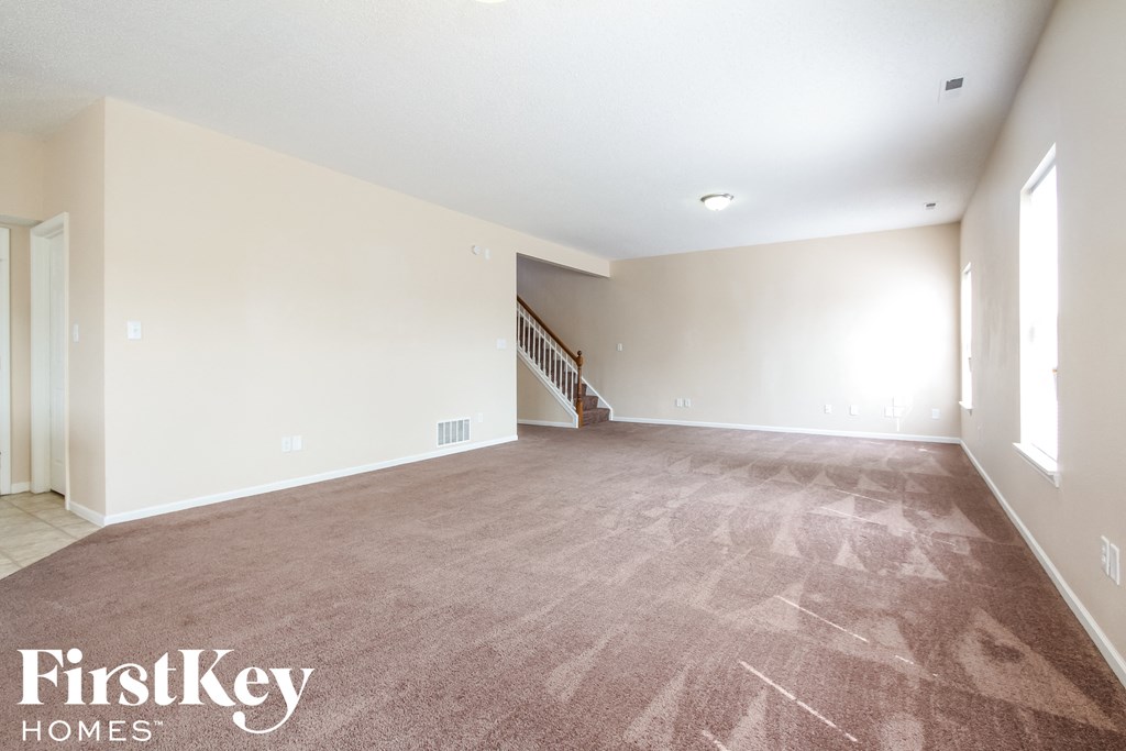 the living room and dining room with carpeted floors and white walls