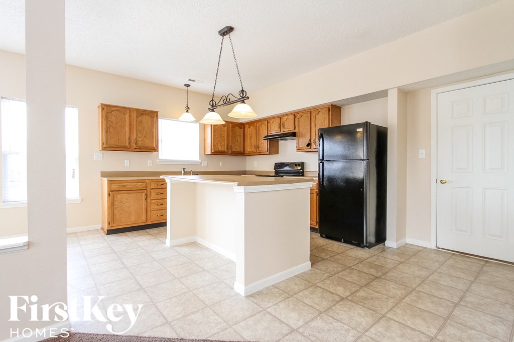 a kitchen with wood cabinets and a black refrigerator