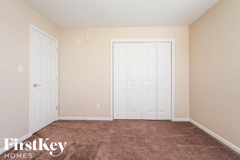a carpeted room with two closets and two doors