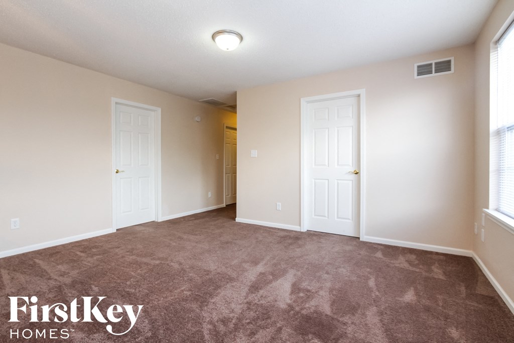 an empty living room with two doors and a carpeted floor
