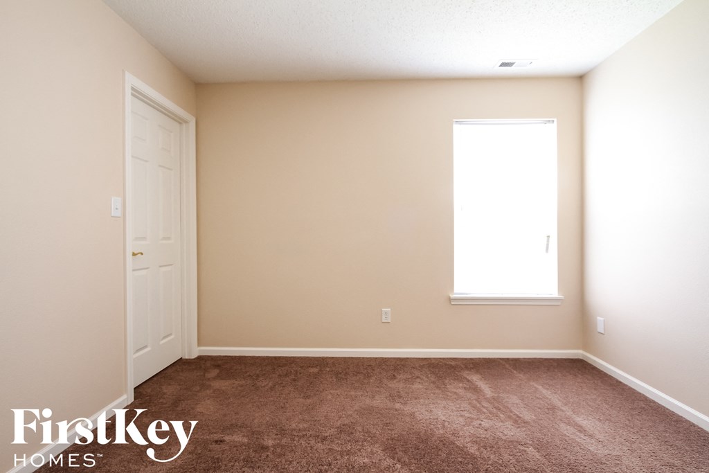 a carpeted room with a door and a window