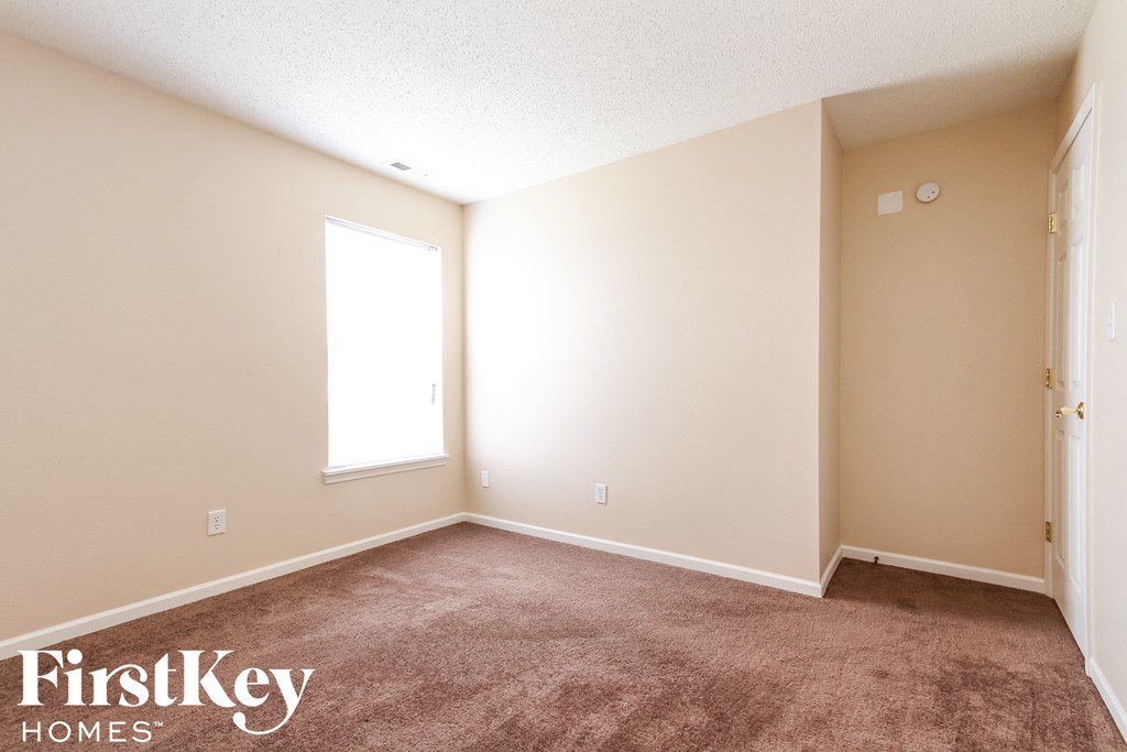 a carpeted room with a window and a door