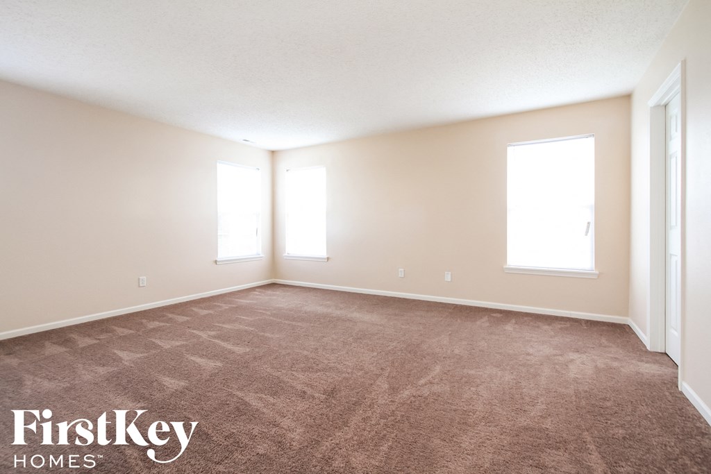 the spacious living room with carpeting and two windows