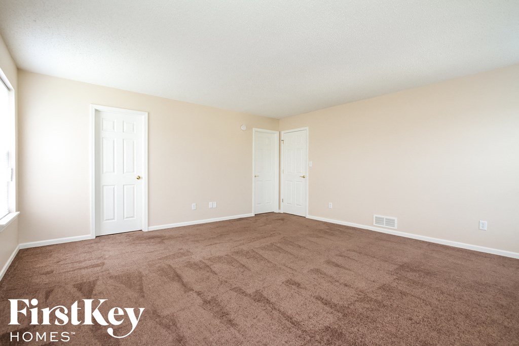 a empty living room with carpet and two doors