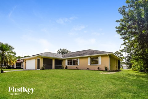 a yellow house with a grassy yard and trees