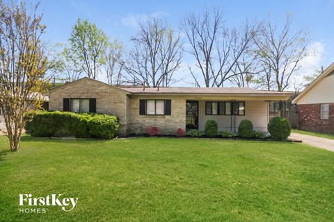 a brick house with black shutters and a green lawn