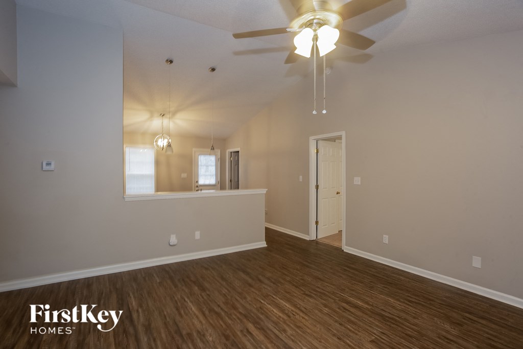 A room with a ceiling fan and wooden floors.