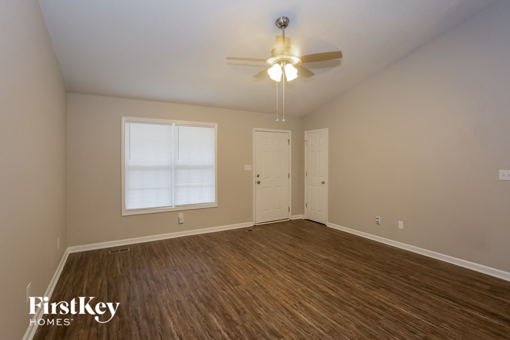 A room with a ceiling fan and wooden flooring.