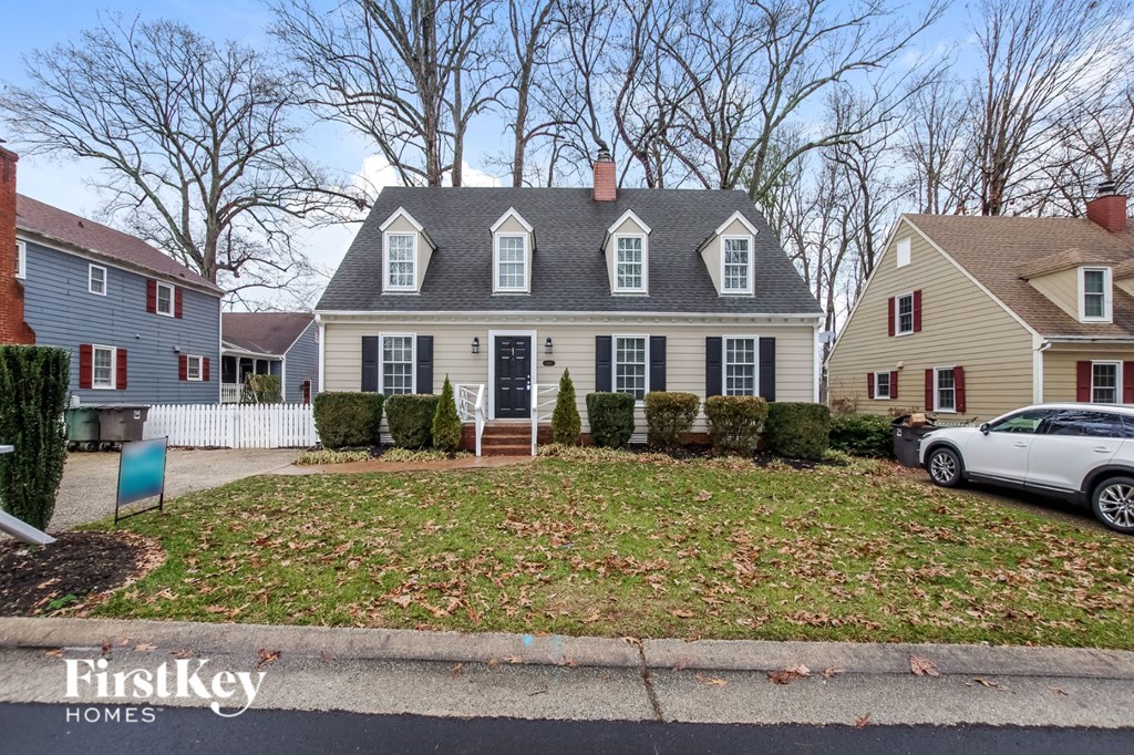 A house with a grey front yard and a white car parked in front.