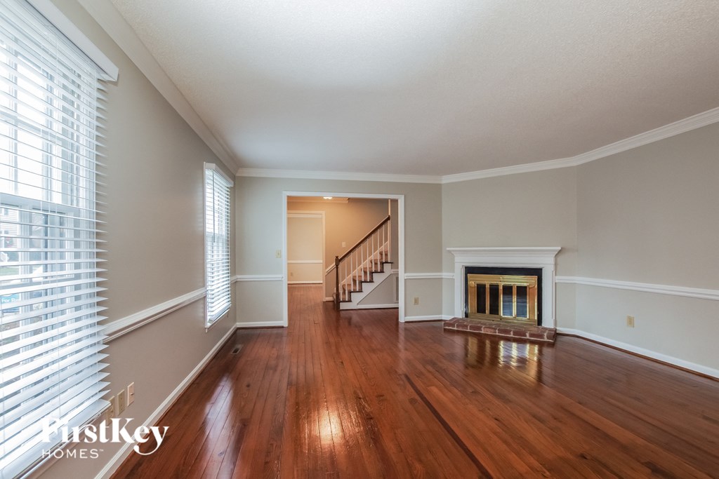 A spacious room with wooden floors and a fireplace.
