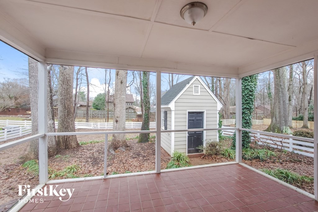 A porch with a view of a house and trees.