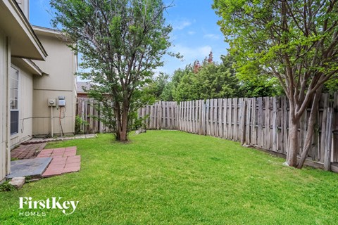 a backyard with a fence and a lawn and trees