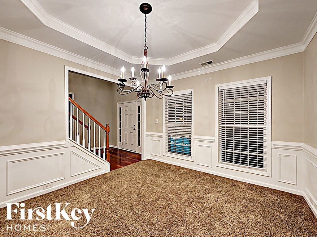 A well-lit room with a chandelier and a carpeted floor.