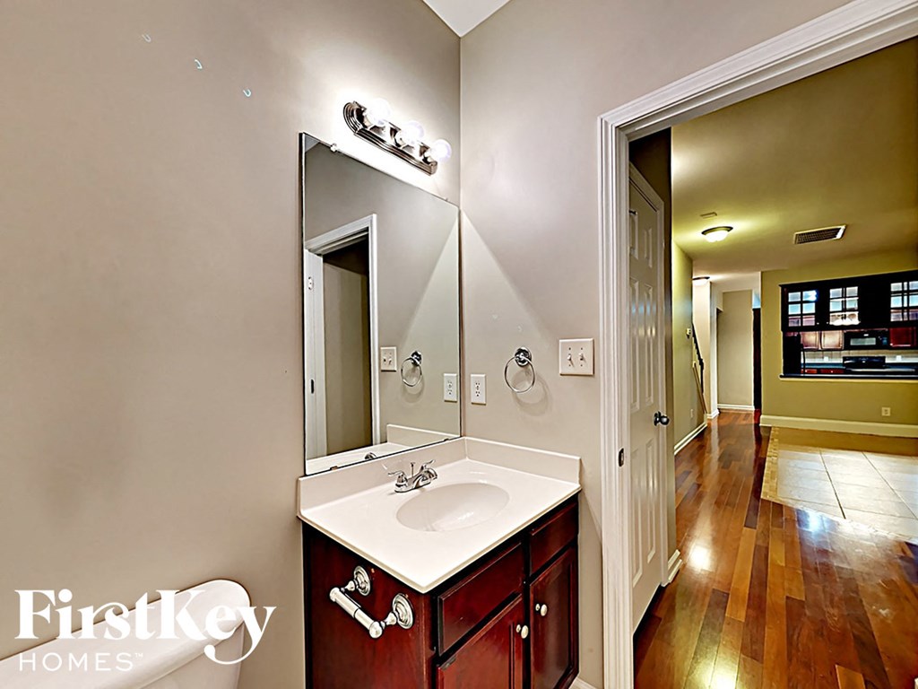 A bathroom with a wooden vanity and a large mirror.