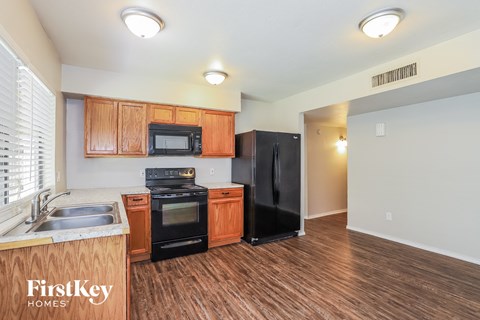 A kitchen with wooden cabinets and a black refrigerator.