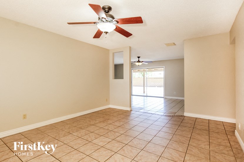 a empty living room with a ceiling fan and a tiled floor