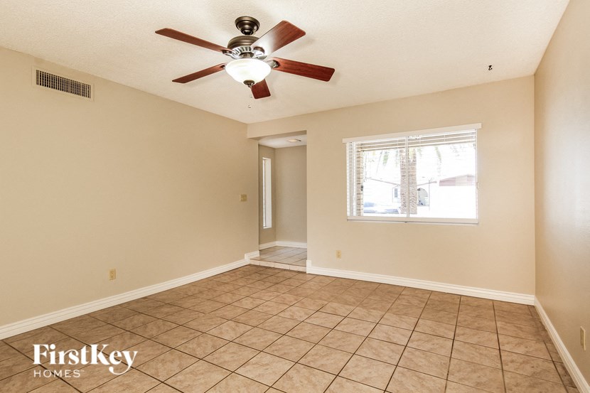 a empty living room with a ceiling fan and a window
