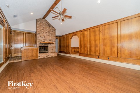 A spacious room with wooden floors and a stone fireplace.