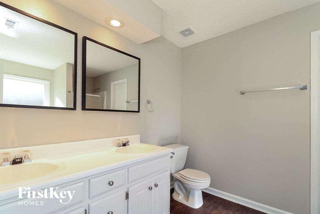 a white bathroom with two mirrors and a toilet and a sink