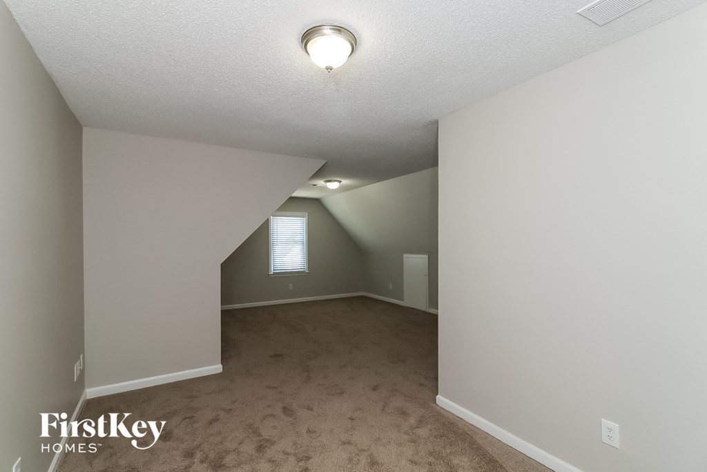 the living room of an attic with a carpeted floor and a window