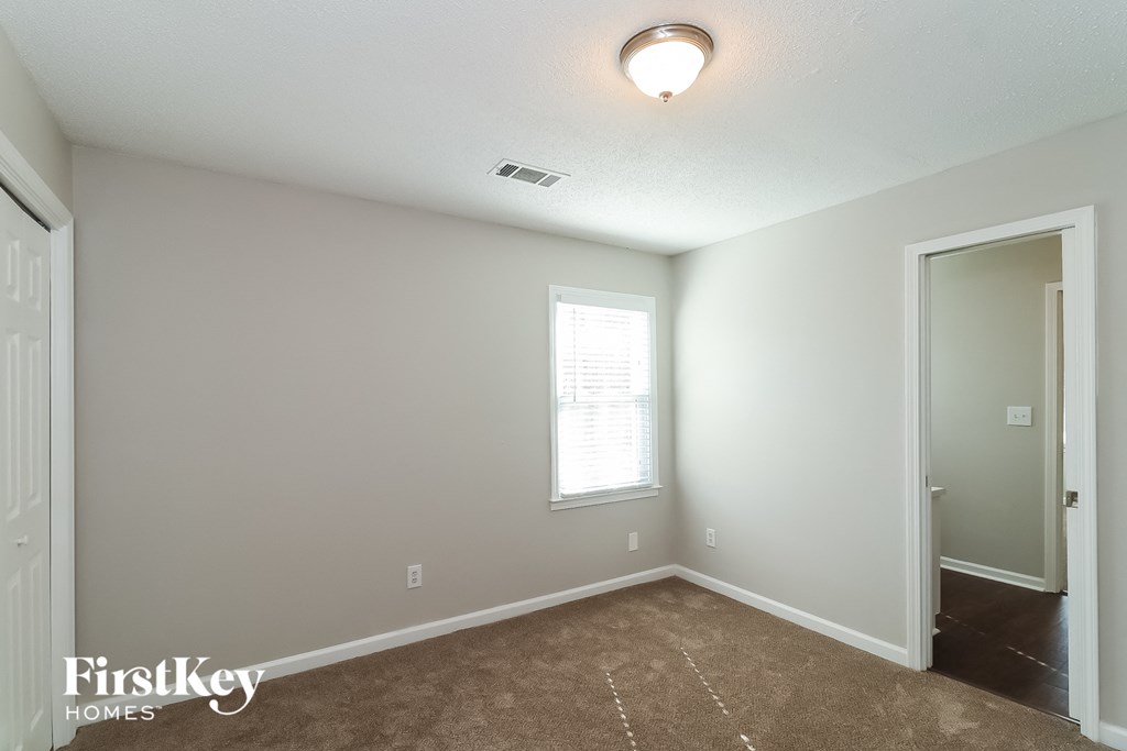 a bedroom with a carpeted floor and a door to a closet