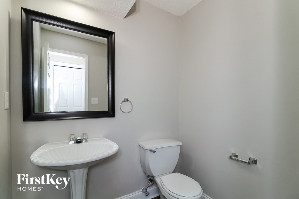 a white bathroom with a mirror and a toilet and a sink