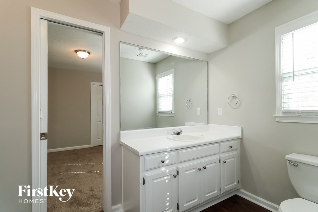 a white bathroom with a large mirror and a white sink and toilet