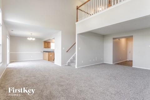 A spacious, empty living room with a staircase leading to the upper floor.