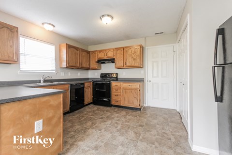 A kitchen with wooden cabinets and a black refrigerator.